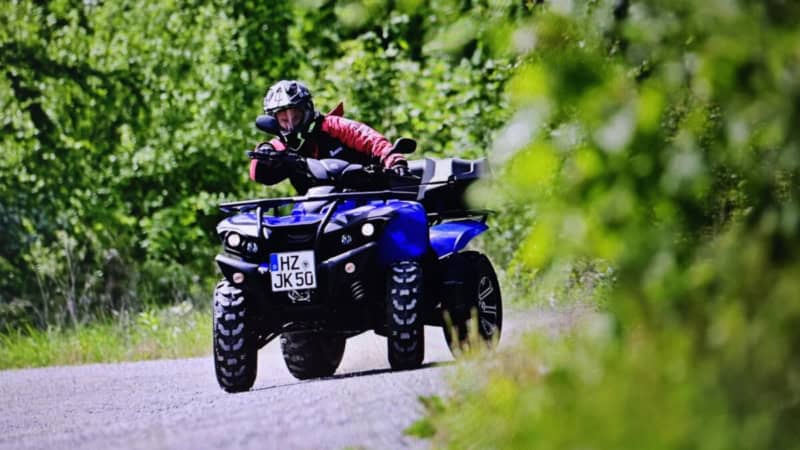 Quad Fahrer auf kurvenreicher Schotterstrecke in rasanter fahrt.
