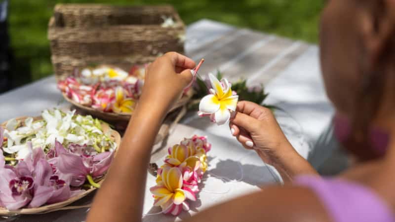 Eine Frau macht Blumenkranz aus Plumeria-Blumen.