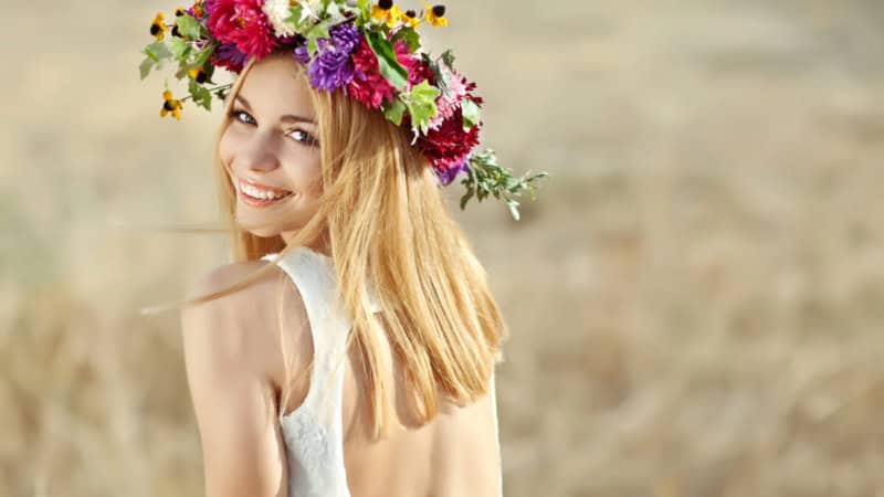 Eine Frau trägt einen selbstgemachten Blumenkranz auf dem Kopf und posiert für ein Foto.
