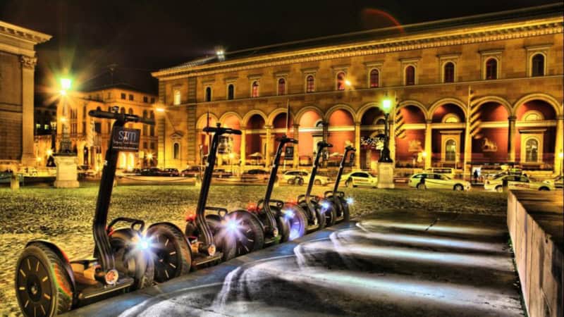 Segways stehen auf der Straße in München in der Nacht und warten auf den Tourbeginn.