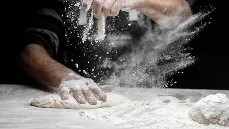 Ein Mann knetet mit den Händen Pizzateig auf einem Tisch - Kochkurs bei Frankfurt