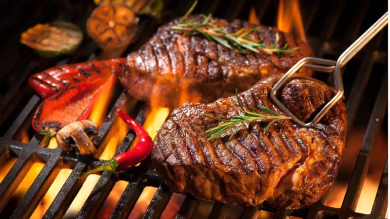 Zwei saftige Steaks, die auf einem Grill gegrillt werden.