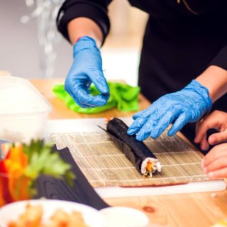 Sushi welches von Kochkursteilnehmern gerollt wird.