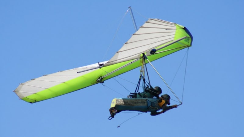 Ein grüner Drachen mit 2 fliegenden wird von hinten fotografiert.