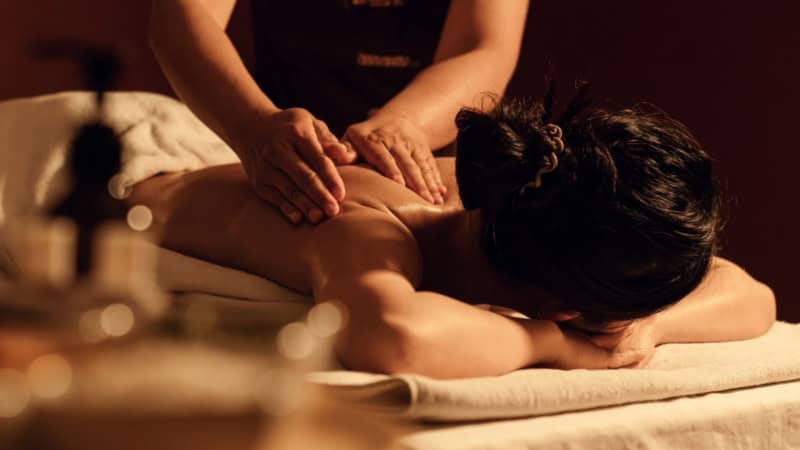 Der Rücken einer Frau wird mit ätherischen Ölen nach der AromaTouch Methode behandelt.