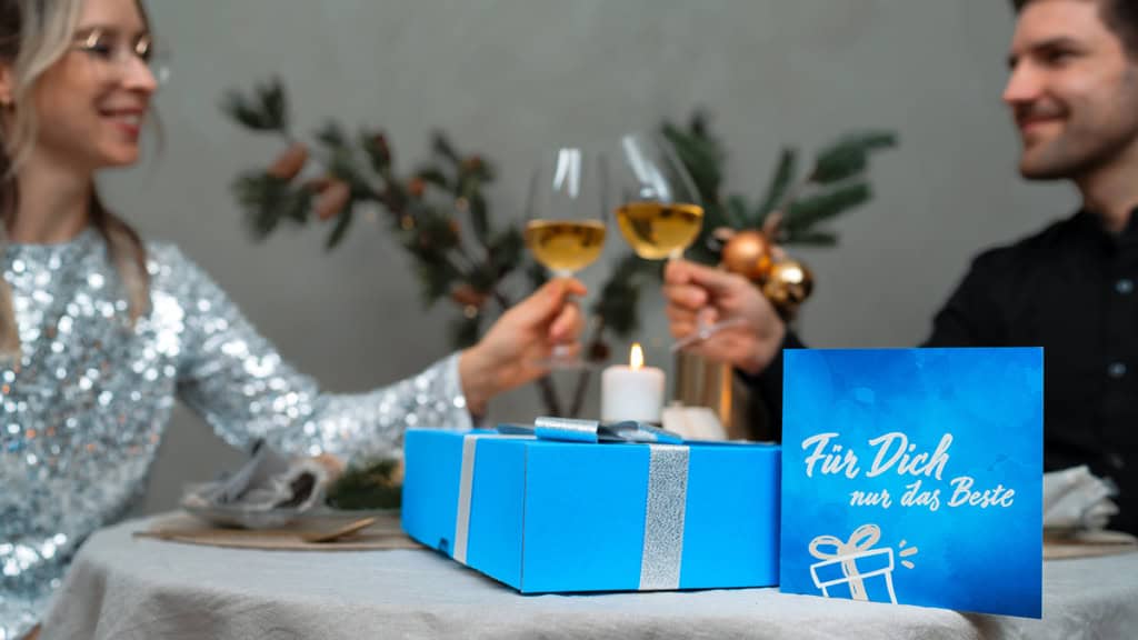 Ein Paar stößt auf die Geschenkte Erlebnis Geschenkbox an Weihnachten an.