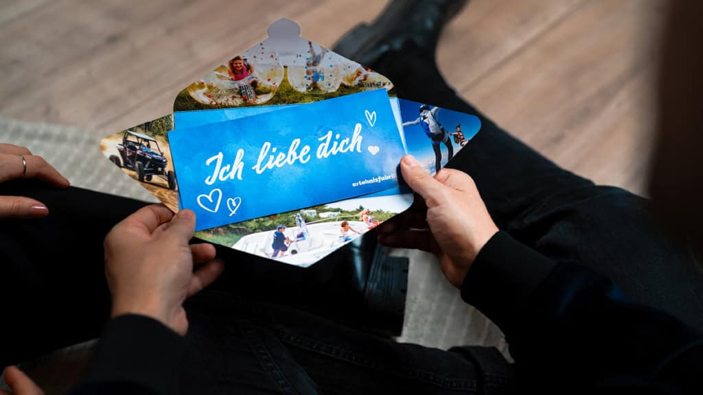 Ein geöffneter Umschlag in dem ein Erlebnisgutschein ist auf dem ich liebe dich steht.