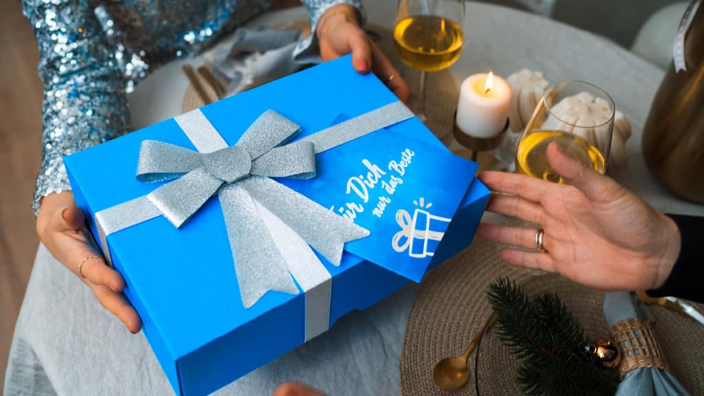Eine Geschenkbox wird am Esstisch zu Weihnachten übergeben.