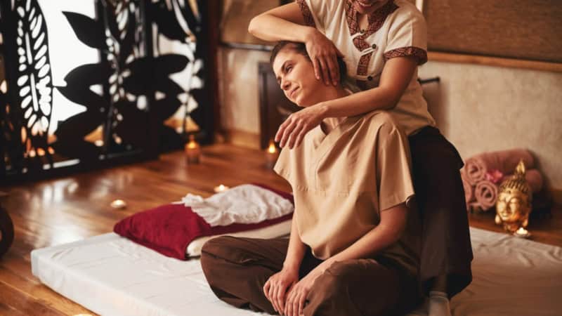 Eine Frau bekommt bei einer traditionellen Thai Massage den Hals gedehnt.