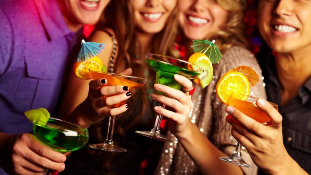 Personen beim anstoßen mit ihren Cocktails in der Hand