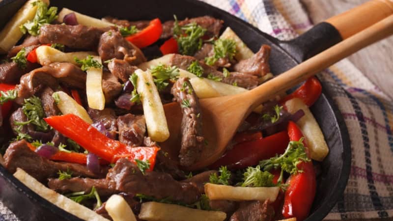 In der Pfanne wird Kartoffel und Rindfleisch gewendet für ein peruanisches Gericht Lomo Saltado.