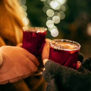 Nahaufnahme eines Paares, das frischen Glühwein in Gläsern in der Hand hält.