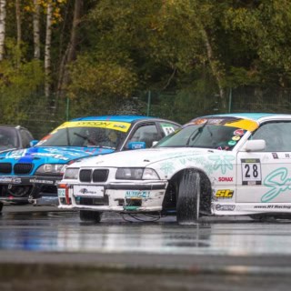 Drei Sportautos driften auf nassem Asphalt am Nürburgring.