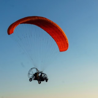 Ansicht auf einen fliegenden, motorisierten, Gleitschirmflieger von unten.
